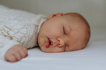 Portrait of cute little baby sleeping in bed, on belly, closed eyes.