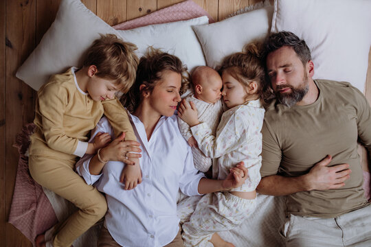 Top view of family sleeping in bed with kids and newborn baby. Perfect moment. Strong family, bonding and parents' unconditional love for their children.