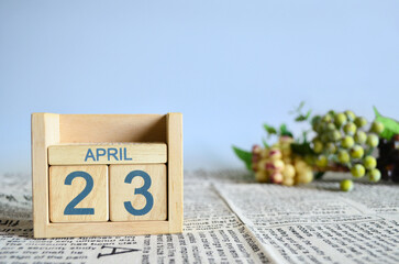 April 23, Calendar cover design with number cube with fruit on newspaper fabric and blue background.	