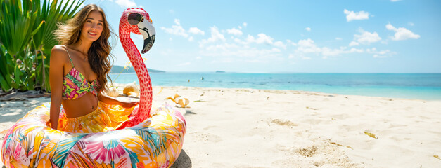 Joyful Woman Relaxing on Flamingo Float at Beach