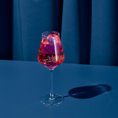Elegant cocktail with red vermouth on blue background with shadow. Vermouth cocktail on coloured...