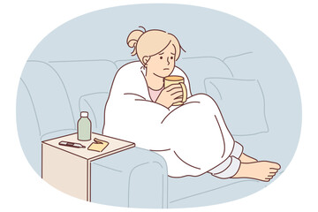 Woman sick with flu wrapped in blanket sits on couch and drinks hot decoction of herbs
