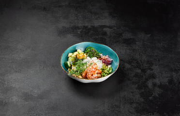 Poke bowl with shrimps and vegetables on black concrete background. Ahi poke with shrimp, rice,...
