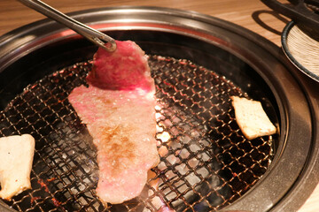 yakiniku Japanese grilled barbecued beef with two pieces of mushroom on the sides. There are smoke...