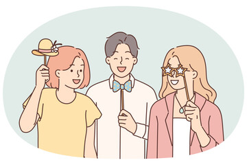 Cheerful friends with photo props pose for joint picture during birthday party or holiday festival