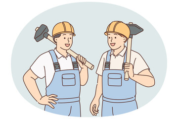 Men in builders uniforms and hardhats hold sledgehammers to demolish wall of emergency building