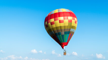 Closeup travel hot air ballon flying with people and blue sky background. Single colorful hot air balloon floating in the air