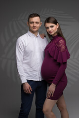 portrait of a pregnant couple on a grey background, pregnant couple