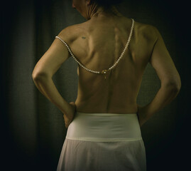 woman seen from behind with a white petticoat-type skirt and a pearl necklace in a romantic...