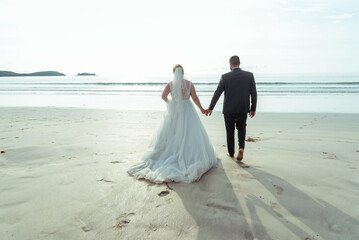 un couple de marié de dos sur la plage - obrazy, fototapety, plakaty