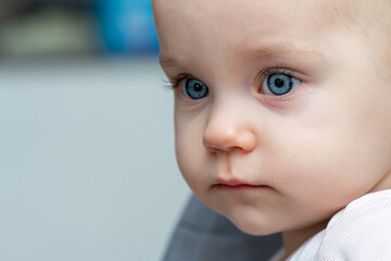 One year old baby gazes to the side with curious eyes. Concept of innocence and wonder in childhood