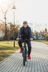 Obraz premium Man Riding Bike Down Sidewalk in a Park