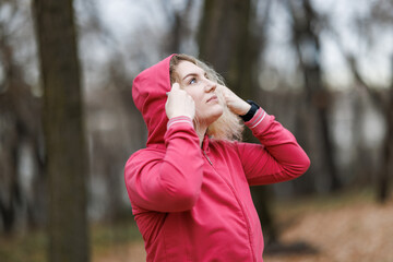 Woman in Jacket Holding Hoodie Over Head And Preparing for Outdoor Training