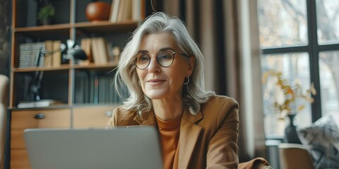 Mature businesswoman in a home office attending a virtual meeting on a laptop and watching an online training webinar. Concept Businesswoman, Home Office, Virtual Meeting, Laptop