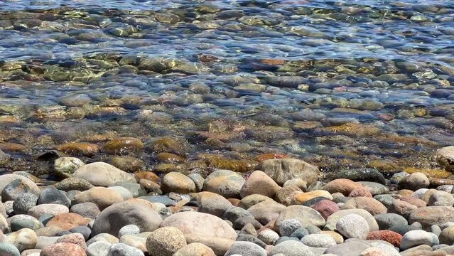 View of Issyk-Kul mountain lake, Kyrgyzstan. Waves splash on a sandy beach with rocks. Calm, peaceful natural background. Lake with a view of the Tien Shan Mountains. Kyrgyzstan 4K