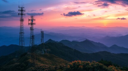 A beautiful sunset over a mountain range with three tall towers in the background. The towers are likely cell phone towers - obrazy, fototapety, plakaty
