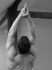 Muscular Yoga Athletic Man doing stretching back exercises. Black and White photography