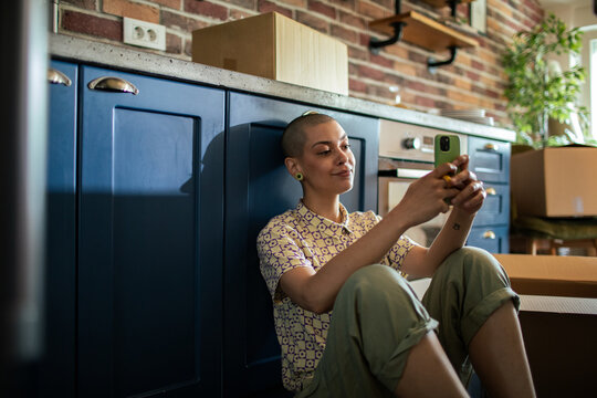 Woman using smartphone on floor with moving boxes around