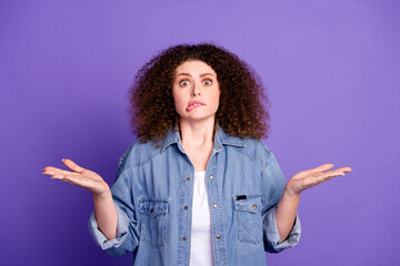 Portrait of pretty young woman bite lips shrug shoulders wear denim shirt isolated on purple color...