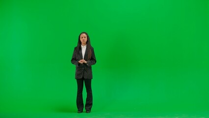 Fototapeta premium Young female reporter isolated on chroma key green screen background. Full shot african american woman tv news host talking with serious face.