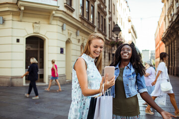 Two women taking a selfie together on a sunny city street