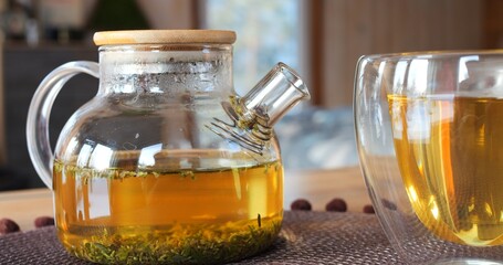 In glass mug, herbal drink aiding in reducing body temperature during illness. On table, freshly...