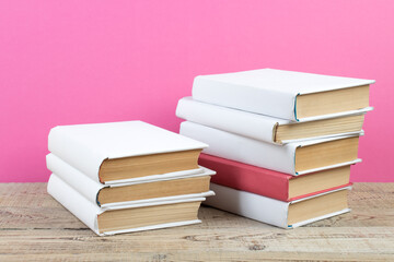 Books stacking. Books on wooden table and pink background. Back to school. Copy space for ad text.