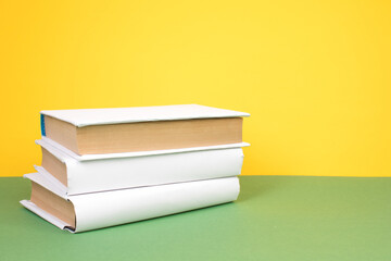 Books stacking. Open hardback books on wooden table and green background. Back to school. Copy space for ad text.