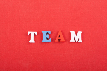 Fototapeta na wymiar TEAM word on red background composed from colorful abc alphabet block wooden letters, copy space for ad text. Learning english concept.