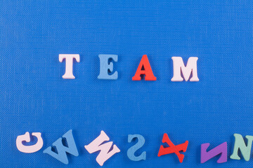 TEAM word on blue background composed from colorful abc alphabet block wooden letters, copy space for ad text. Learning english concept.