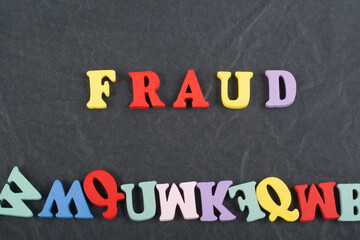 FRAUD word on black board background composed from colorful abc alphabet block wooden letters, copy space for ad text. Learning english concept.
