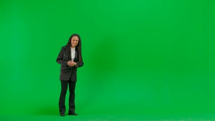 Young female reporter isolated on chroma key green screen background. Full shot african american woman tv news host talking smiling at camera.