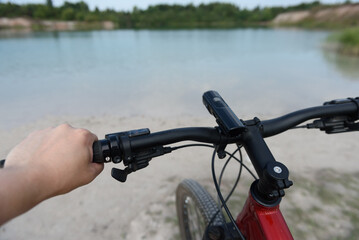 Obraz premium close view of bicycle handlebar with panoramic view of lake
