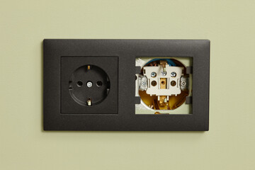 Electrical outlet with black matte frame on light green background