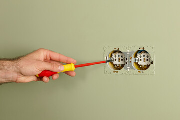 Man installing electrical outlet on the wall with a screwdriver - 773346189