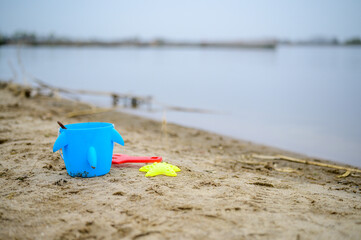Wiaderko z zabawkami porzucone przez dziecko. Chroń swoje dziecko nad wodą - obrazy, fototapety, plakaty