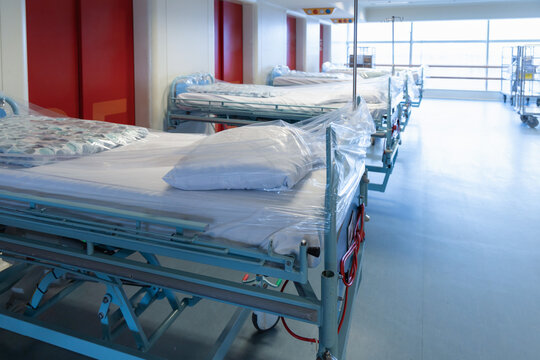 Clean hospital beds covered with film, ready for new patients.