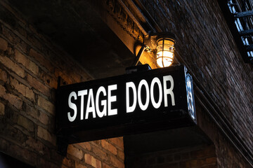 Vintage illuminated stage door sign in a dark and dingy back alley in the city of Chicago, Illinois, USA