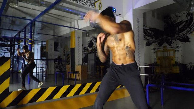 Young afro american sportsman practicing shadow boxing at modern gym. Muscular african boxer demonstrating punches the air indoor. Strong black kickboxer training at fitness centre. Healthy lifestyle