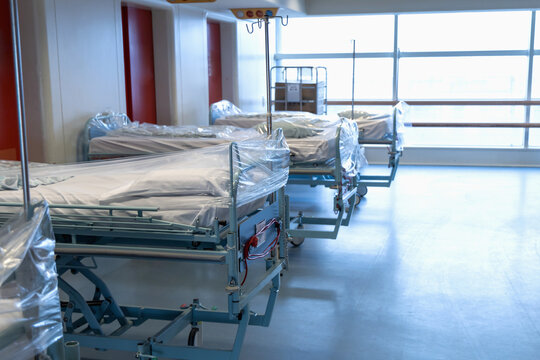 Clean hospital beds covered with film, ready for new patients.