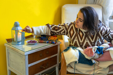 Young woman knitting in a house lights a candle