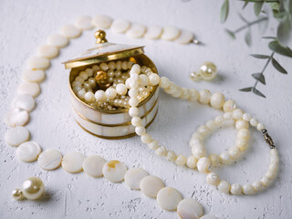 Mother-of-pearl gold box with pearl jewelry on a white table. - 773369938