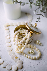 Mother-of-pearl gold box with pearl jewelry on a white table.