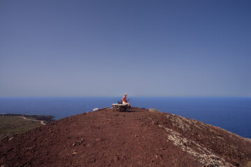 A woman looking the sea from the top of the volcano called Monte Nero, Linosa