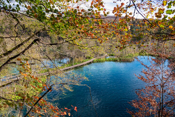 Enchanting hiking trail on rustical wooden footpath in magical Plitvice lakes National Park, Karlovac, Croatia, Europe. Walking over calm waters in serene nature. Idyllic autumn landscape. Wanderlust