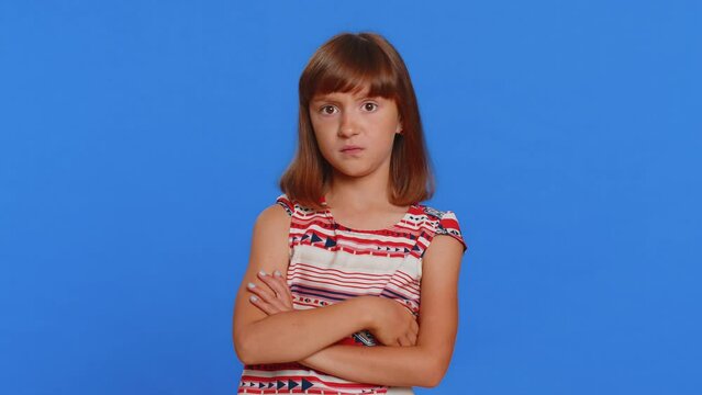Cheerful funny young brunette school girl showing tongue making faces at camera, fooling around, joking, aping with silly face, teasing, bullying, abuse. Preteen female child kid on blue background