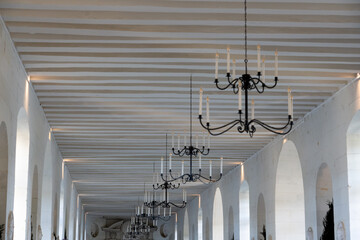 a long hallway with chandeliers and candles, a large white country mansion with normandy style...