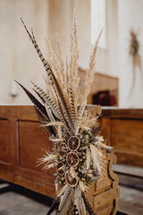 Bouquet de fleurs séchées et de plumes décorant les bancs de l'église