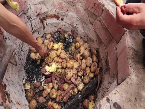 Video of unknown people taking the pachamanca out of an oven. Concept of food preparation.
