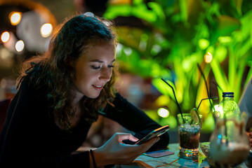 Young girl using mobile phone in a bar.